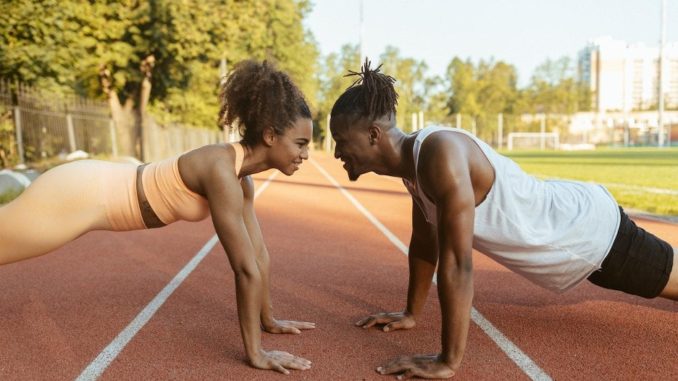 man and woman doing push-ups on a running track