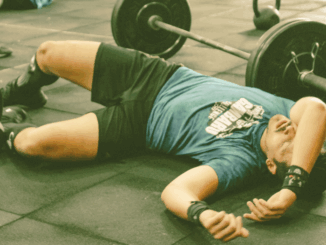 Man lying on gym floor due to fatigue after weight lifting
